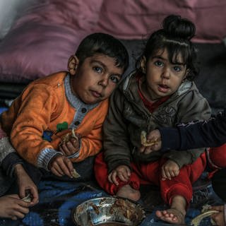 Vertriebene palästinensische Kinder essen Bohnen in einem Zelt.