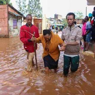 IMAGO  Xinhua (Foto: IMAGO, Anwohner helfen einer Frau während Überschwemmungen nach heftigen Regenfällen in den Armenvierteln von Mathare in Nairobi, Kenia)