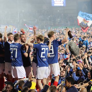 Spieler von Holstein Kiel feiern mit den Fans im Stadion den ersten Aufstieg in die Fußball Bundesliga. 