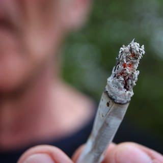 Ein Mann hält einen Joint.  Jede und jeder Zweite in Deutschland mag den Geruch von Cannabis nicht. Das ist das Ergebnis einer YouGov-Umfrage. (Foto: dpa Bildfunk, picture alliance/dpa | Karl-Josef Hildenbrand)