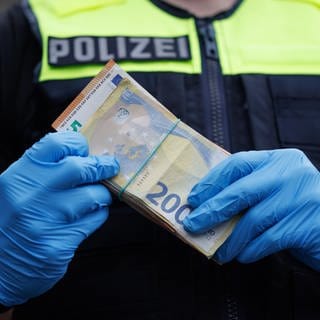 Ein Polizeibeamter mit einer größeren Menge Bargeld in der Hand.