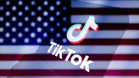 Das TikTok-Logo wird auf einem Smartphone vor dem Hintergrund der abgeschnittenen US-Fahne angezeigt.