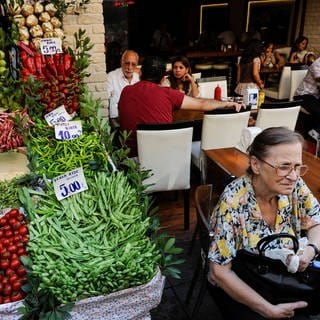Ein Restaurant mit Menschen neben einem Gemüsestand in Istanbul (Archiv). (Foto: IMAGO, IMAGO / Joerg Boethling)