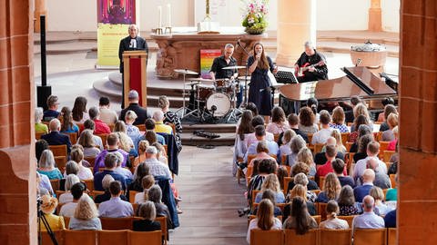 Sängerin Tine Wiechmann tritt in der Heiliggeistkirche während eines Taylor-Swift-Gottesdienstes auf. Links im Bild steht Pfarrer Vincenzo Petracca. Die Künstlerin sang mit ihrer Band sechs Lieder des Popstars. Die beiden Messen mit dem Titel «Anti Hero» nach dem Song «Anti-Hero» von Swift waren ausgebucht.