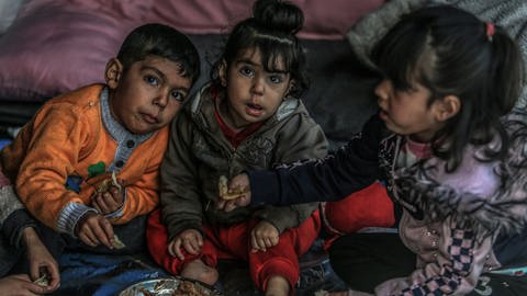 Vertriebene palästinensische Kinder essen Bohnen in einem Zelt.