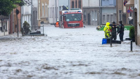 Überflutete Straße im Saarland: Die Feuerwehr kämpft sich durchs Wasser, Menschen müssen evakuiert werden