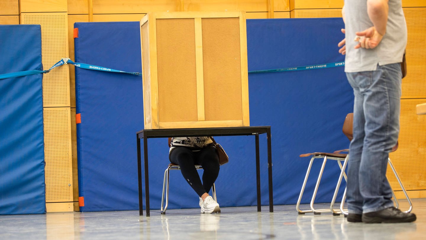 Menschen in der Wahlkabine und Aushaendigung der Stimmzettel in einem Wahllokal in Berlin am 26. September 2021.