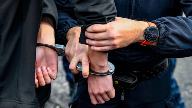 Polizist verhaftet Mann und legt ihm Handschellen um.  (Foto: IMAGO, IMAGO / Andia)
