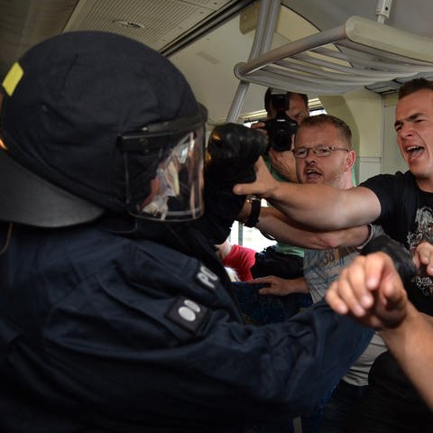 Bundespolizist in einer körperlichen Auseinandersetzung mit gewaltbereiten Fußballfans in einem Wagon der Bahn.