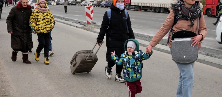 An einer Straße gehen Flüchtlinge aus der Ukraine entlang, es sind Frauen und Kinder. (Foto: dpa Bildfunk, picture alliance/dpa/AP | Czarek Sokolowski)