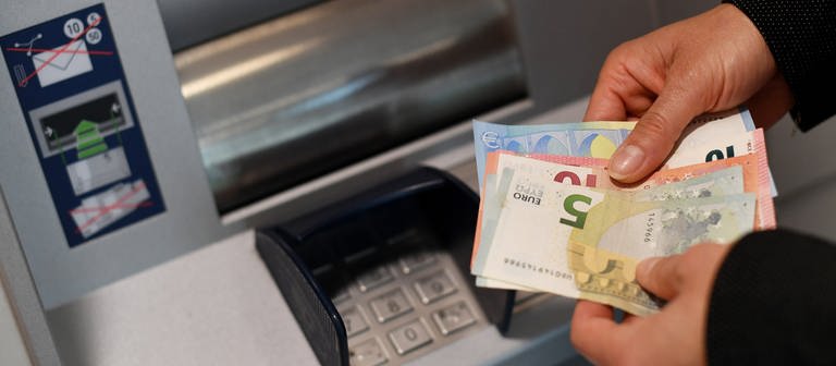 Eine Frau hebt in einer Bankfiliale Geld am Automaten ab (Foto: dpa Bildfunk, picture alliance/dpa | Angelika Warmuth)