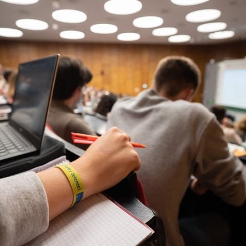 Eine Studentin sitzt mit einem 2G-Armband in der Vorlesung Mathematik für die Erstsemester des Bachelors Wirtschaftswissenschaften im Audimax in der Universität Hannover.  (Foto: dpa Bildfunk, picture alliance/dpa | Julian Stratenschulte)