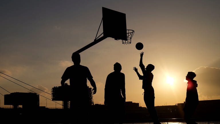 Jugendliche spielen in der Abendsonne am Rheinufer Basketball. (Foto: dpa Bildfunk, picture alliance/dpa | Oliver Berg)