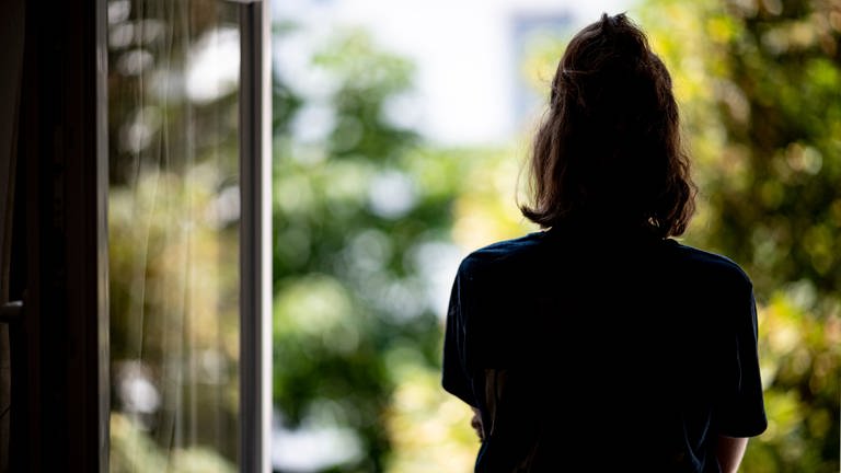 Eine Frau steht in ihrer Wohnung an einem Fenster (Foto: dpa Bildfunk, picture alliance/dpa | Fabian Sommer)