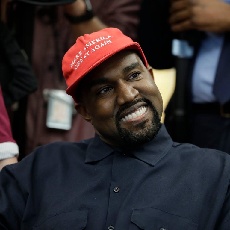 Der US-Rapper Kanye West sitzt während eines Treffens mit US-Präsident Trump und anderen im Oval Office im Weißen Haus und trägt dabei eine rote Mütze mit der Aufschrift «Make Amerika Great Again». (Foto: dpa Bildfunk, picture alliance/dpa | Evan Vucci)