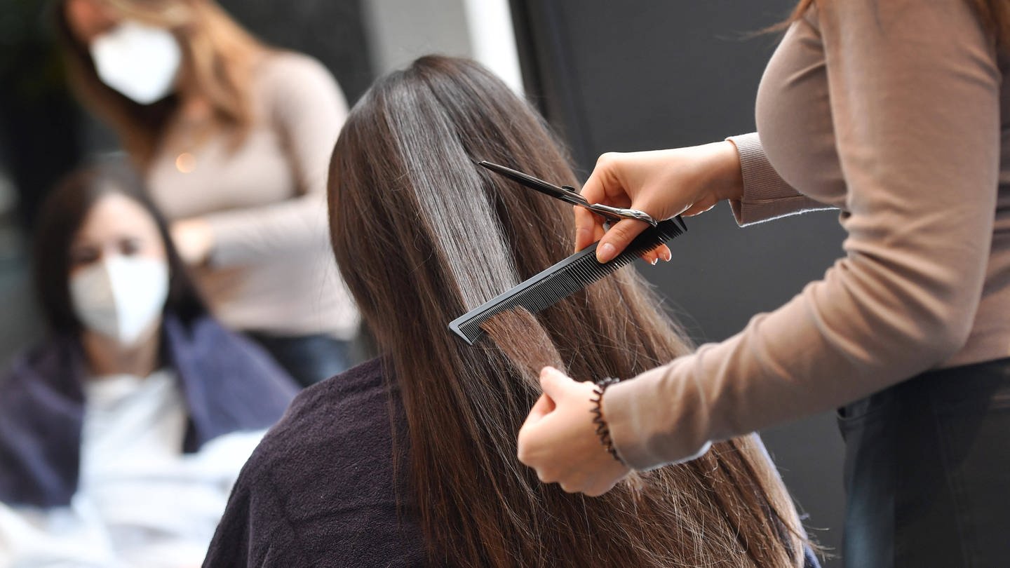 Eine Friseurin schneidet ein Kundin die Haare.  (Foto: IMAGO / Sven Simon)