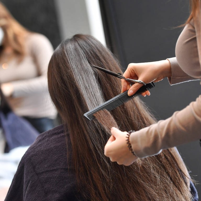 Eine Friseurin schneidet ein Kundin die Haare.  (Foto: imago images, IMAGO / Sven Simon)