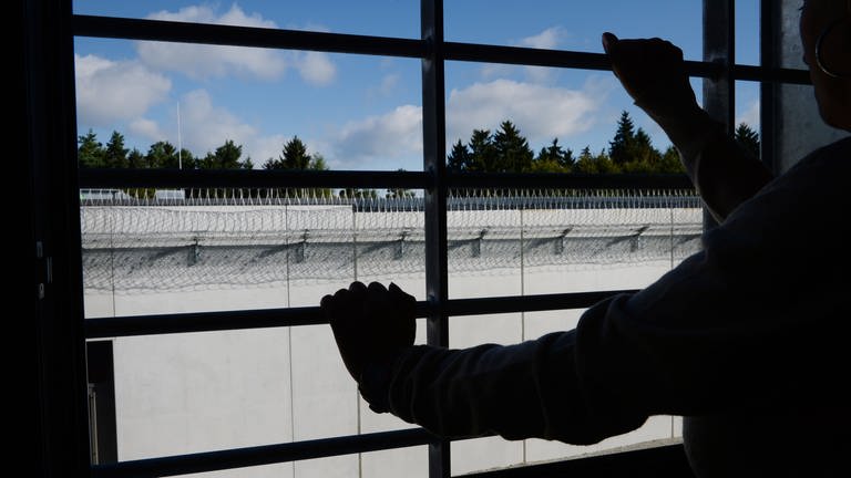 Ein Häftling stehtim Neubau der Justizvollzugsanstalt an einem vergitterten Fenster in einer Zelle. (Foto: dpa Bildfunk, picture alliance/dpa | Felix Kästle)