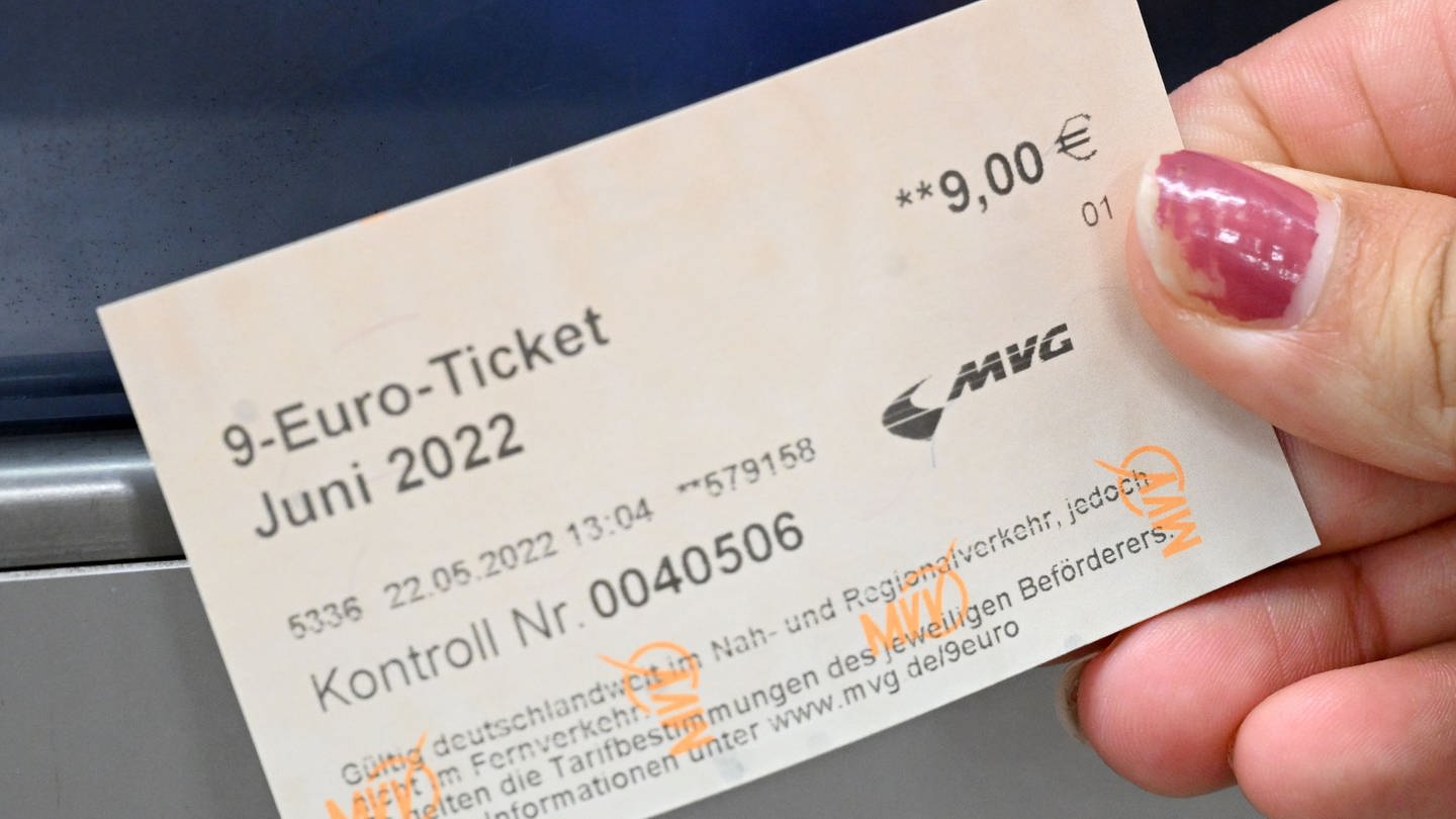 Ein 9-Euro-Ticket wird von einer Hand nah in die Kamera gehalten.