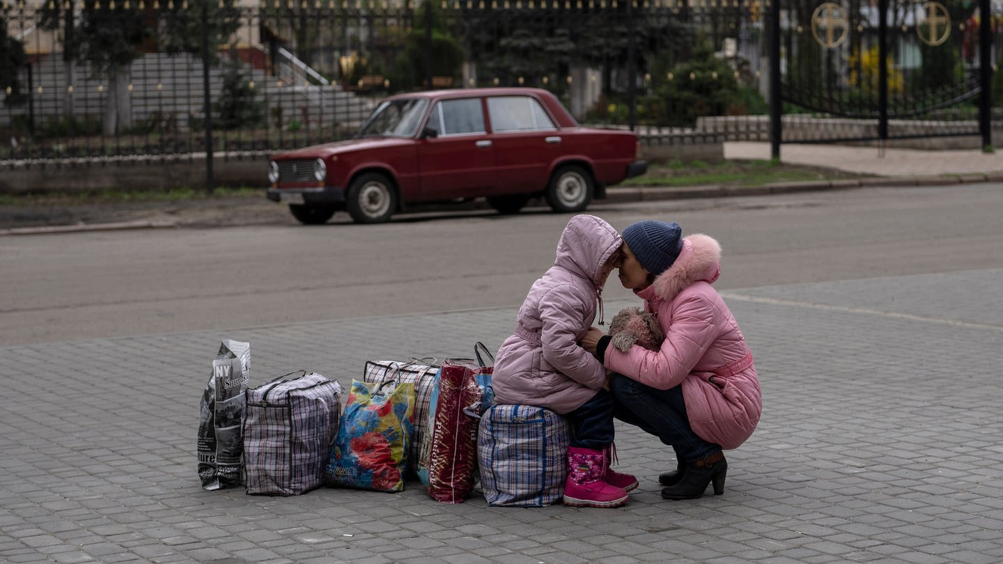 Eine Mutter umarmt ihre Tochter, während sie auf einen Bus warten, um aus der Stadt Slowjansk im Bezirk Donezk nach Riwne im Nordwesten der Ukraine zu fliehen.