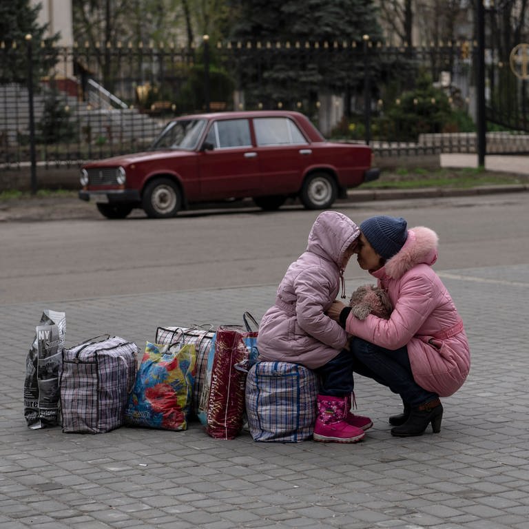 Eine Mutter umarmt ihre Tochter, während sie auf einen Bus warten, um aus der Stadt Slowjansk im Bezirk Donezk nach Riwne im Nordwesten der Ukraine zu fliehen. (Foto: dpa Bildfunk, picture alliance/dpa/AP | Petros Giannakouris)