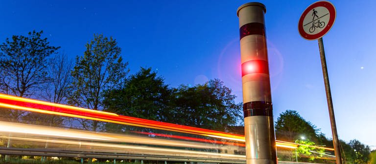 Ein rotes Licht kommt aus einem Blitzer, der an einer Straße steht. (Foto: IMAGO, IMAGO / MiS)