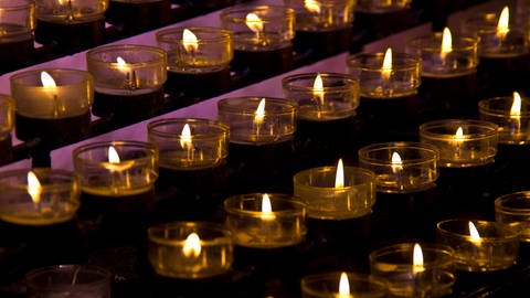 Reihen brennender Kerzen in einer Kirche. (Foto: IMAGO, IMAGO / YAY Images)