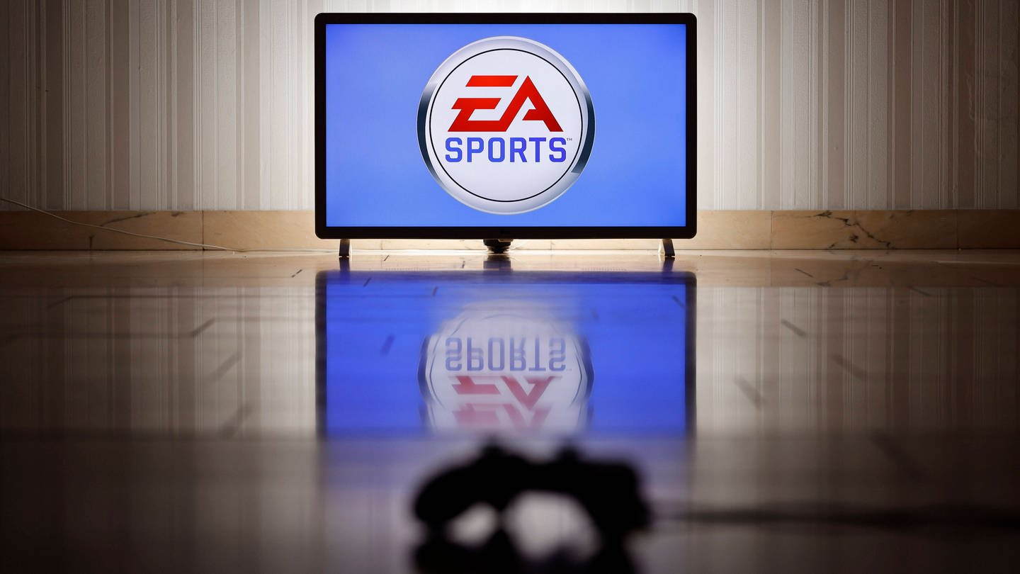 Das Logo der Marke EA Sports des US-amerikanischen Videospielentwicklers und -publishers Electronic Arts auf einem Bildschirm, im Vordergrund ein Gaming-Controller