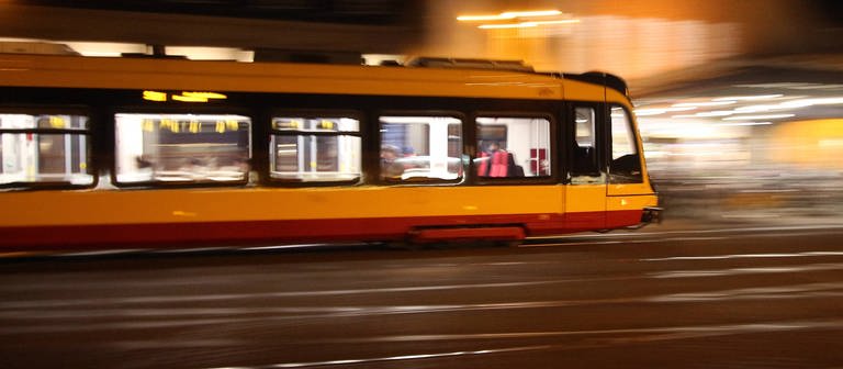Stadtbahn der AVG fährt am Abend vor dem Karlsruhe Hauptbahnhof (Foto: IMAGO, IMAGO / Ralph Peters)