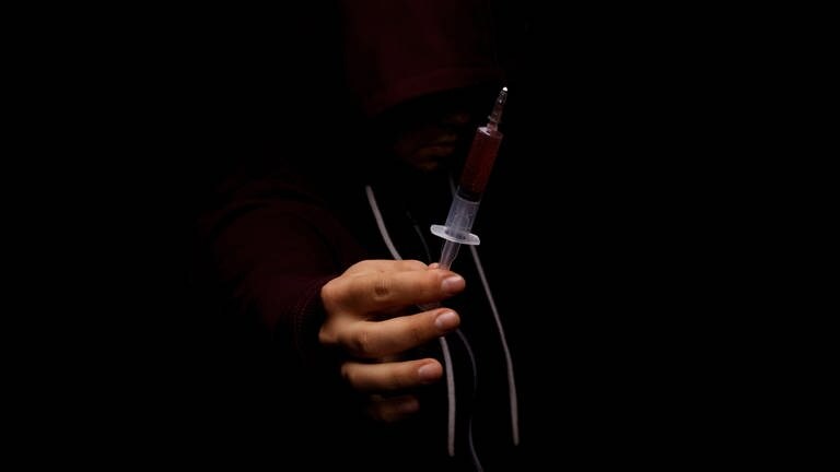 IMAGO  agefotostock (Foto: IMAGO, Close-up of man s hand holding a drug syringe on a black background.)