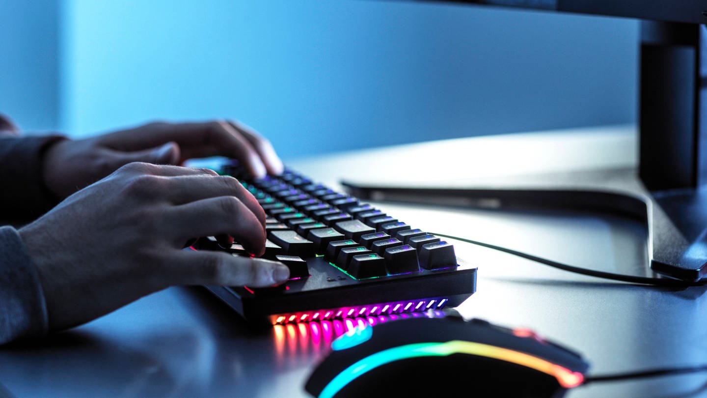Teenager zockt am PC mit einer Tastatur