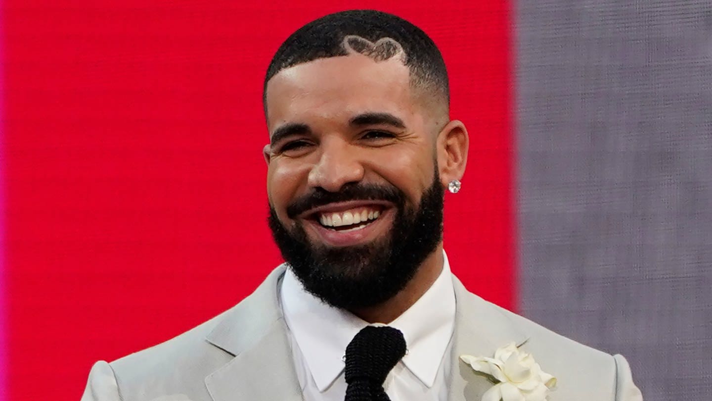 Drake, Rapper und R&B-Sänger, lächelt in weißem Anzug.