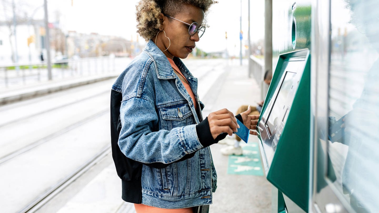 Woman using kiosk at tram station model released Symbolfoto
