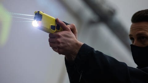 Ein Polizeibeamter demonstriert einen Schuss mit einem Distanzelektroimpulsgerät (DEIG oder auch Taser) (Foto: dpa Bildfunk, picture alliance/dpa | Rolf Vennenbernd)