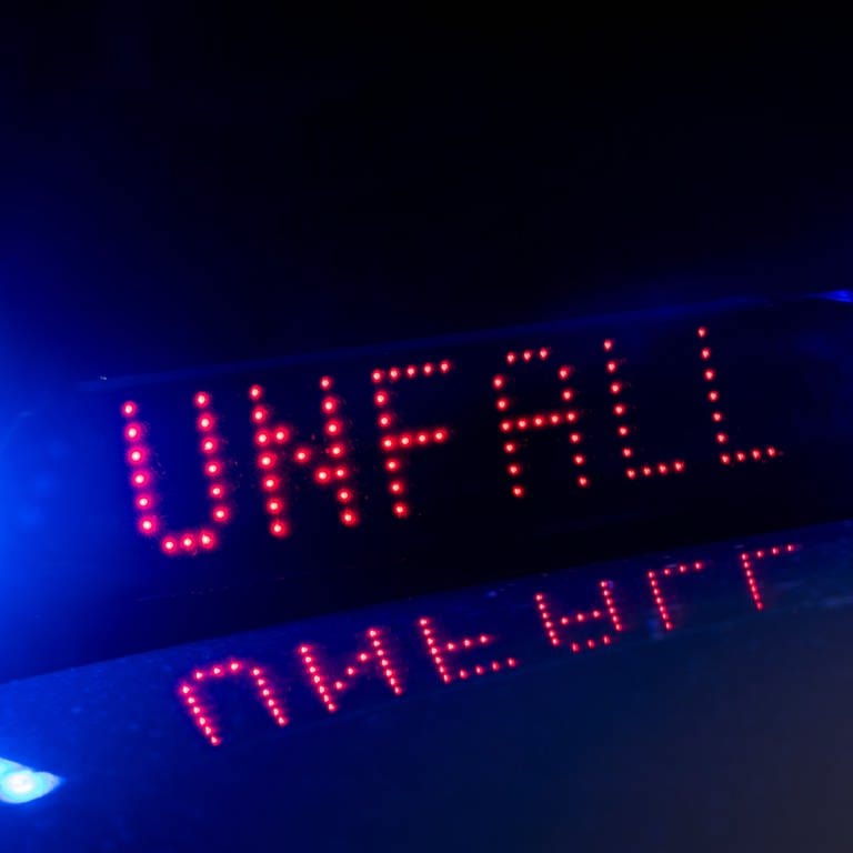 Das Blaulicht auf einem Fahrzeug der Polizei leuchtet in der Dunkelheit, während auf dem Display der Hinweis «Unfall» zu lesen ist.  (Foto: dpa Bildfunk, picture alliance/dpa | Monika Skolimowska)