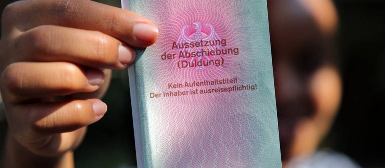Ein ausweis-ähnliches Dokument mit der Aufschrift "Duldung" wird in die Kamera gehalten. (Foto: dpa Bildfunk, picture alliance/dpa | Wolfgang Kumm)