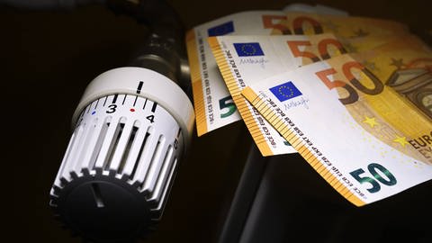 Auf einer Heizung liegen drei 50-Euro-Scheine. (Foto: IMAGO, IMAGO / Christian Ohde)