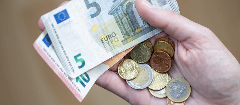 In einer Hand liegen etwa 20 Euro - aufteilt in Münzen und je einem 5- und 10-Euro-Schein. (Foto: dpa Bildfunk, picture alliance/dpa | Daniel Karmann)