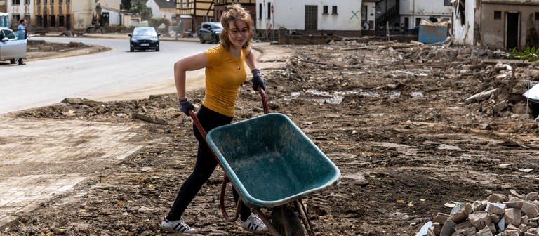 Flutkatastrophe im Ahrtal. Eine junge Helferin hat ihre Schubkarre auf einen Schutthaufen entleert. (Foto: IMAGO, IMAGO / Bonnfilm)