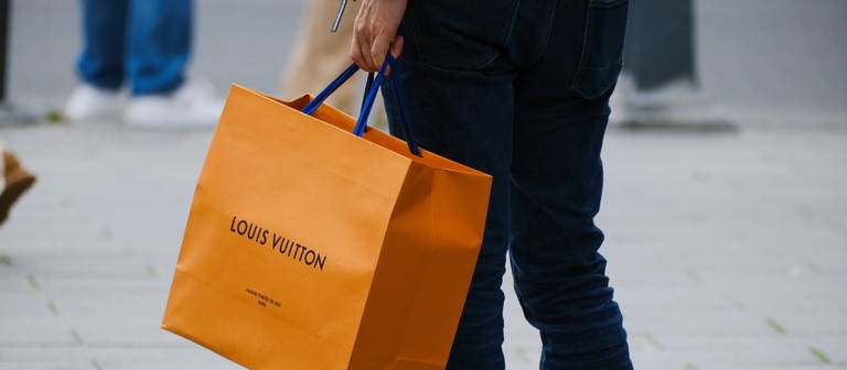 Mann mit Einkaufstasche von Louis Vuitton (Foto: IMAGO, IMAGO / Michael Gstettenbauer)