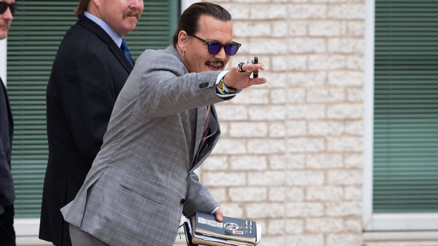 Johnny Depp winkend und lächelnd vor dem Gerichtssaal.