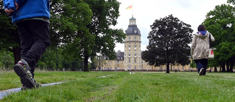 Personen gehen durch den Karlsruher Schlossgarten der wieder geöffnet hat. (Foto: dpa Bildfunk, picture alliance/dpa | Uli Deckpicture alliance/dpa | Uli Deck)