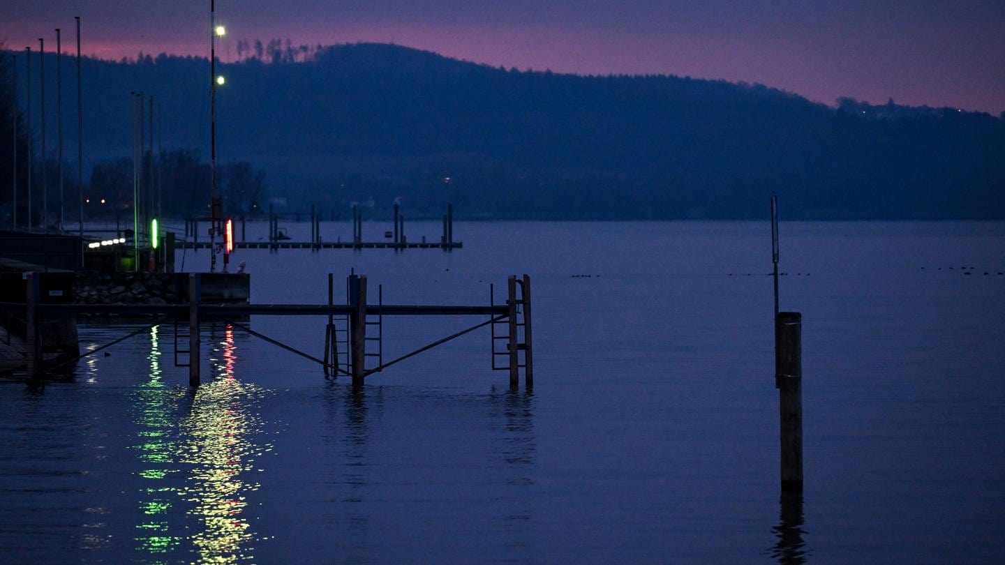 Die Beleuchtung des Yachthafens spiegelt sich zur Blauen Stunde im Bodensee.