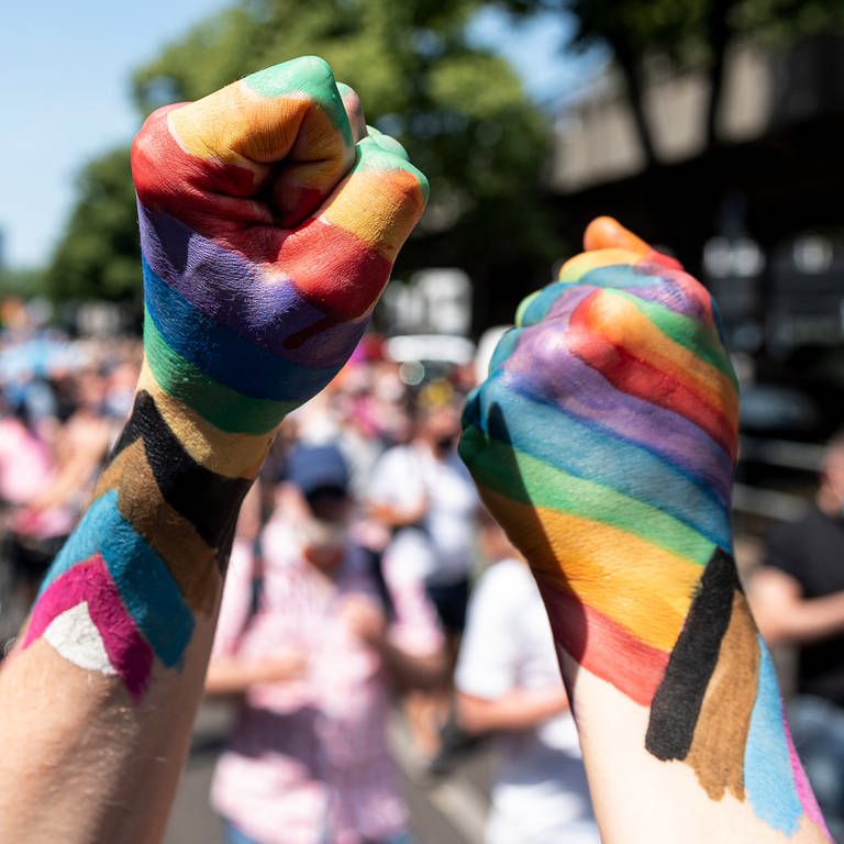 Zwei Teilnehmer der «Pride Berlin: Save our Community, Save our Pride» halten ihre Faust in die Höhe, die in Regenbogenfarbe angemalt sind. (Foto: dpa Bildfunk, picture alliance/dpa | Fabian Sommer)