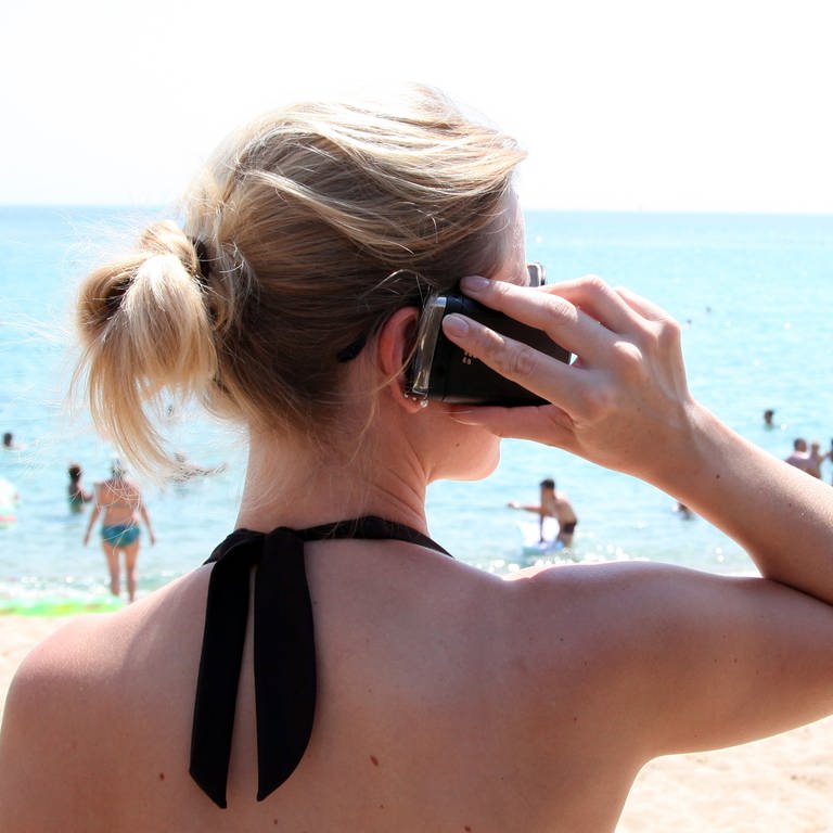 Eine Frau steht mit Handy am Strand. (Foto: dpa Bildfunk, picture alliance / Friso Gentsch/dpa | Friso Gentsch)