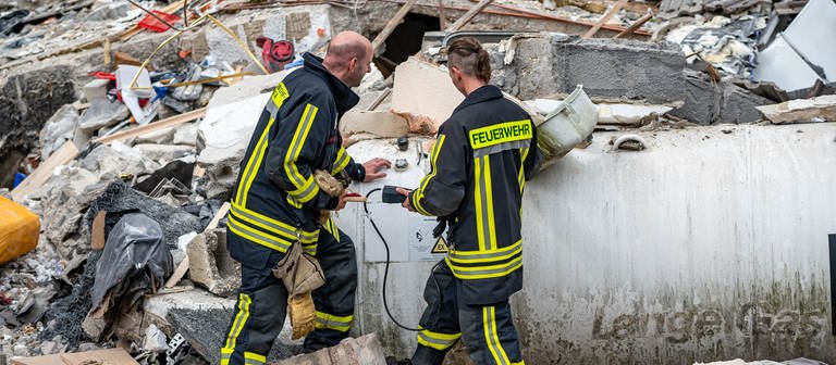 Feuerwehrleute machen eine Messung an einem Gastank zwischen den Trümmern. (Foto: dpa Bildfunk, picture alliance/dpa/Sauerlandreporter | Markus Klümper)
