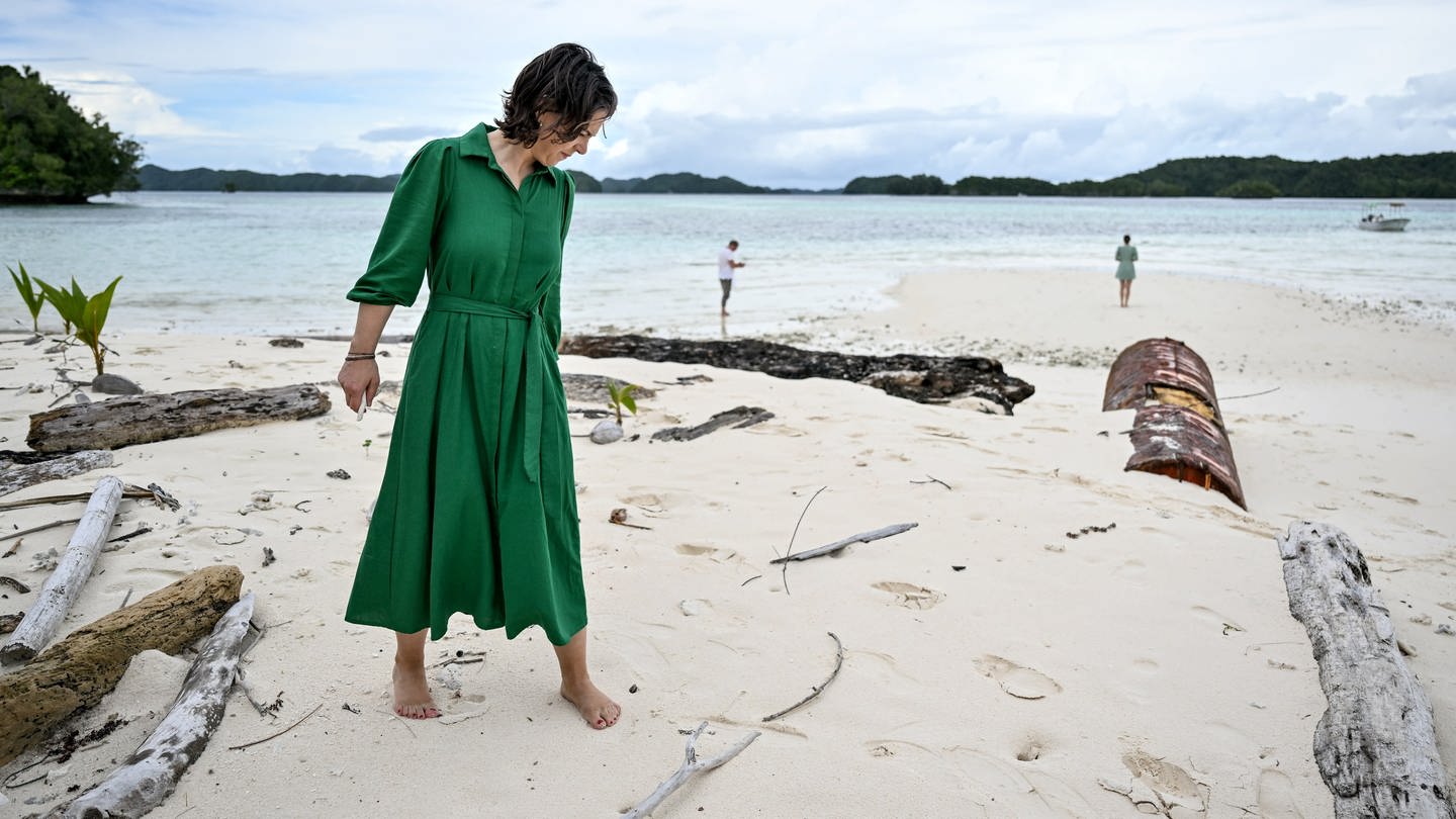 Außenministerin Annalena Baerbock auf der Pazifikinsel Palau zwischen umgestürzten Bäumen.