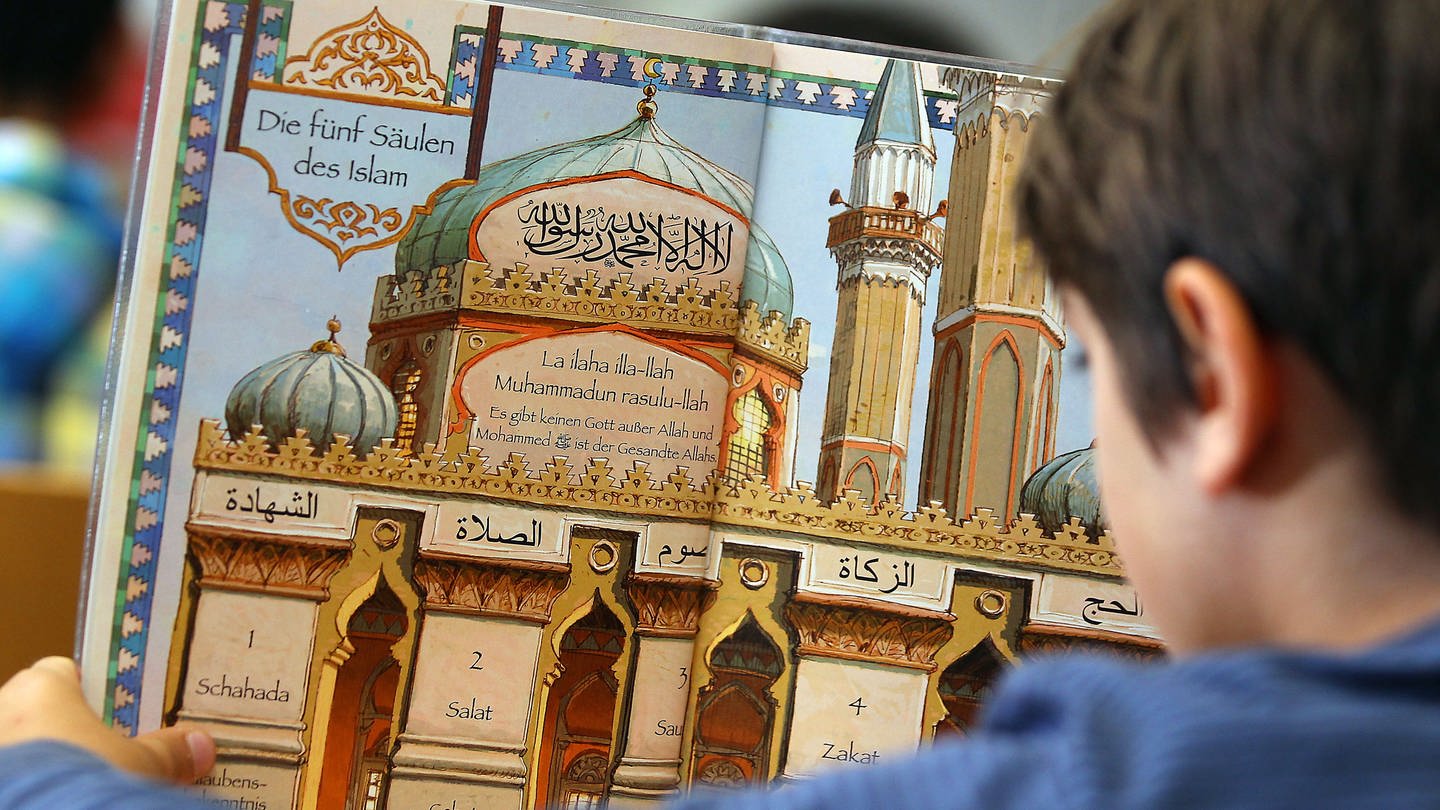 Ein Junge liest während des islamischen Religionsunterrichts in einem Schulbuch.