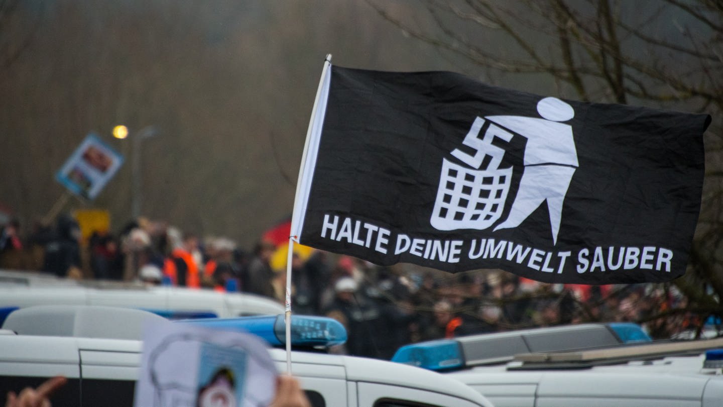 Eine Fahne mit einem Anti-Nazi Symbol wird nach oben gehalten.
