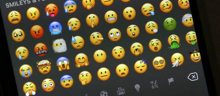 Auf einem Smartphone-Display sind sehr viele Smiley-Emojis zu sehen. (Foto: IMAGO, IMAGO / Rene Traut)